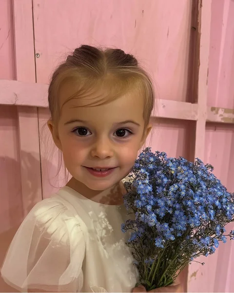 The photo: a little girl in a white dress against a pink wall
