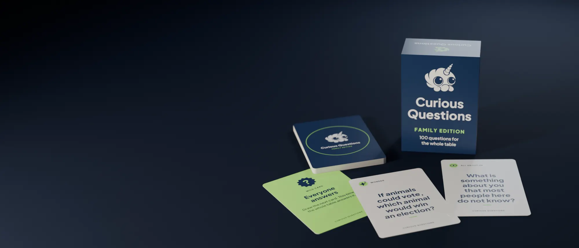 The Curious Questions box and deck on a dark table, three cards dealt face up