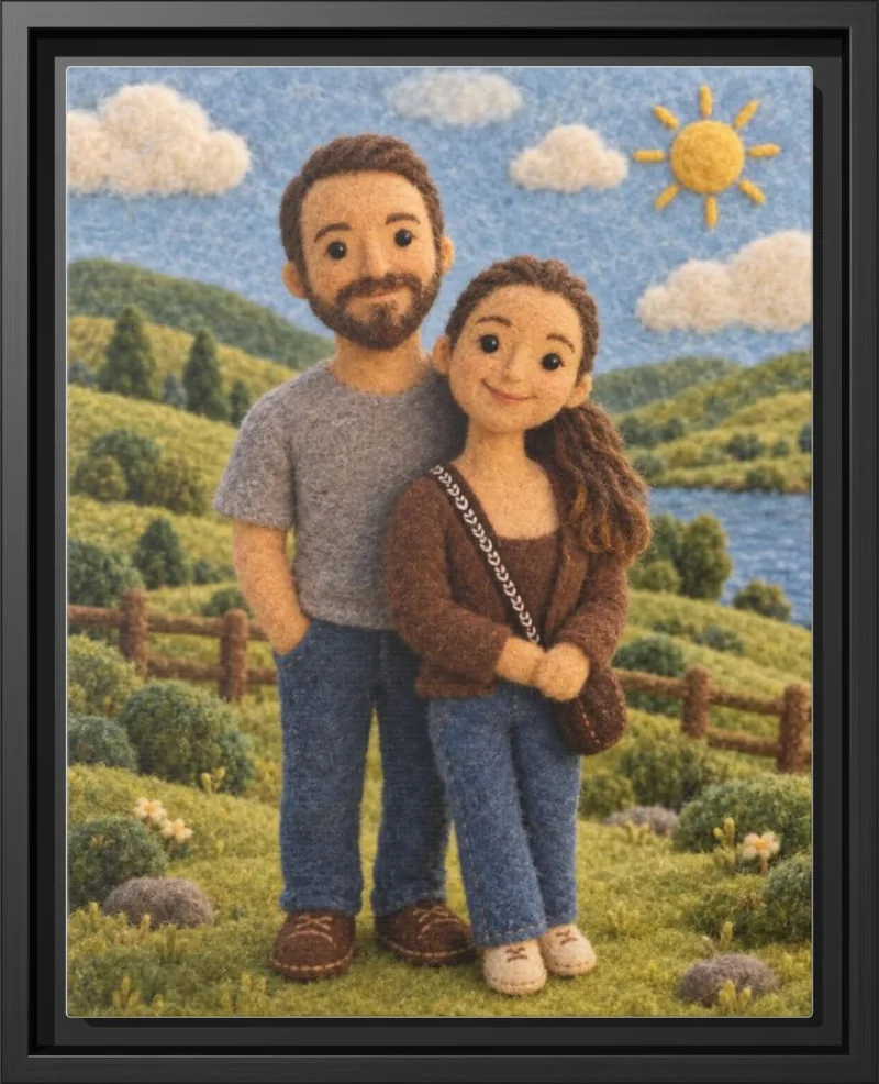 A couple rendered as needle-felted wool figures on a green hillside, in a black floating frame
