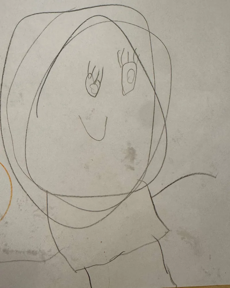 A child's pencil drawing of a smiling girl with big looping hair