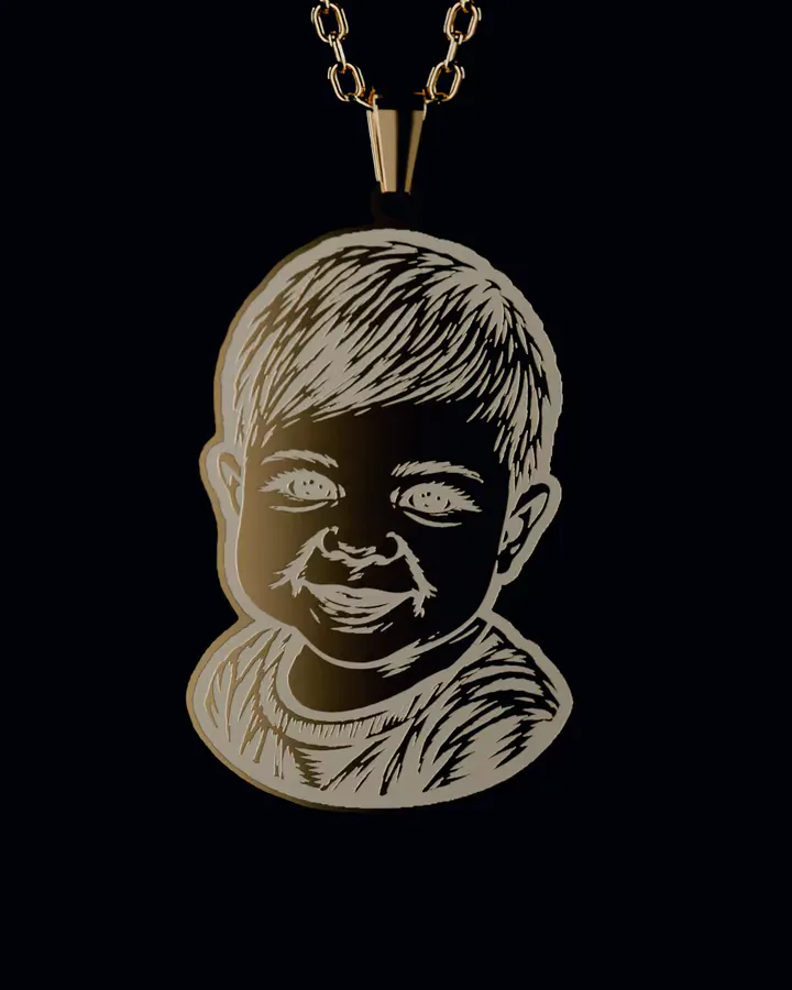 A gold pendant cut to the shape of a boy's portrait, engraved as a linocut, hanging on its chain